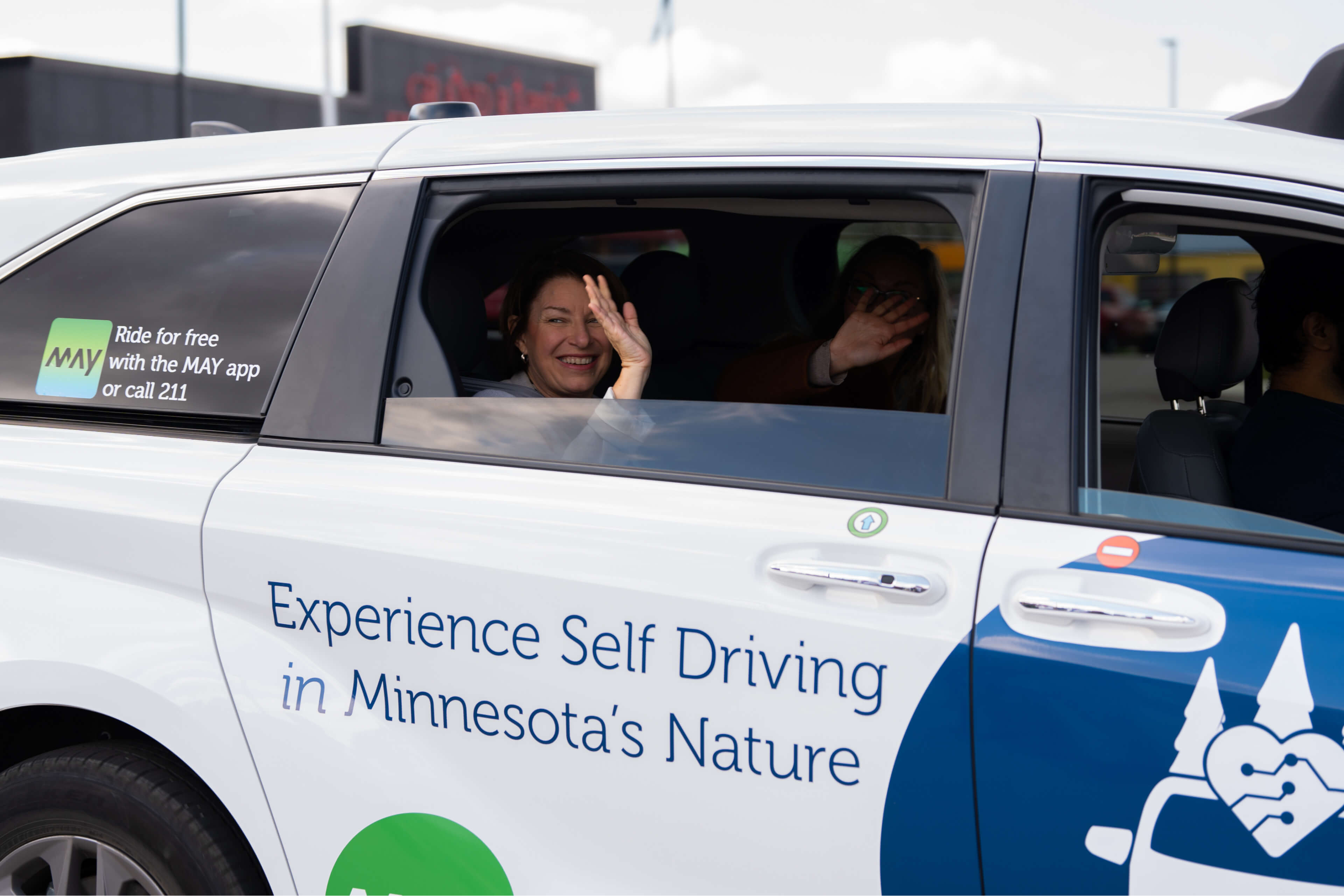 U.S. Senator Amy Klobuchar waves out the window of a goMarti shuttle.