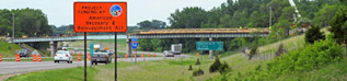 Orange sign by a highway with information about the American Recovery and Reinvestment Act.