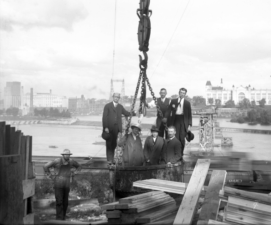 Alderman McInerny and  others seated in a cableway bucket on the west side of the river