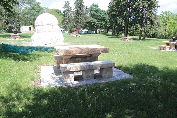 picnic area with stone table in front of stone “beehive” oven under a white cover