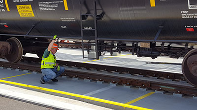 Employee inspecting hazardous materials rail tank car