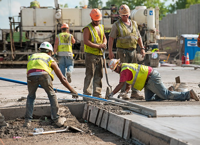 Workers in yellow vests construct a roadway.