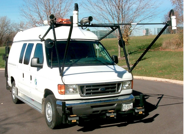 The digital pavement inspection vehicle a white van with three accelerometers mounted across the front bumper facing the road surface.