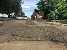 Truck adding geogrid between pavement layers.