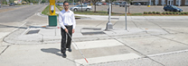 A vision-impaired citizen navigates a crosswalk.