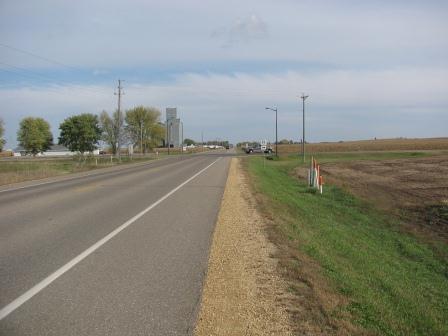 Rural two lane paved road with a sign showing a county highway.