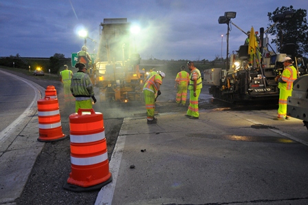 workers paving roadway at night